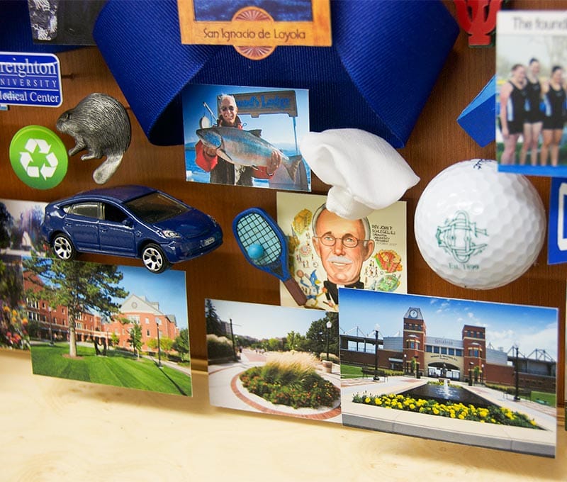 Large collage with over 65 items for the president of Creighton University. Close-up showcases miniaturized images and 3D items including a golf ball, mini car, and chef's hat.