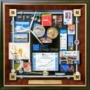 WEC Energy Retirement Gift presented to CEO . Features miniature windmill, Stock Exchange medallion, ID card, growth chart, groundbreaking shovel, miniature hard hat. The border is created with miniature energy pipes. Logo is on the 4 cornerstones.