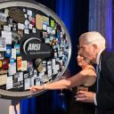 People looking at large shadow box collage commemorating ANSI's 100th Anniversary on stage