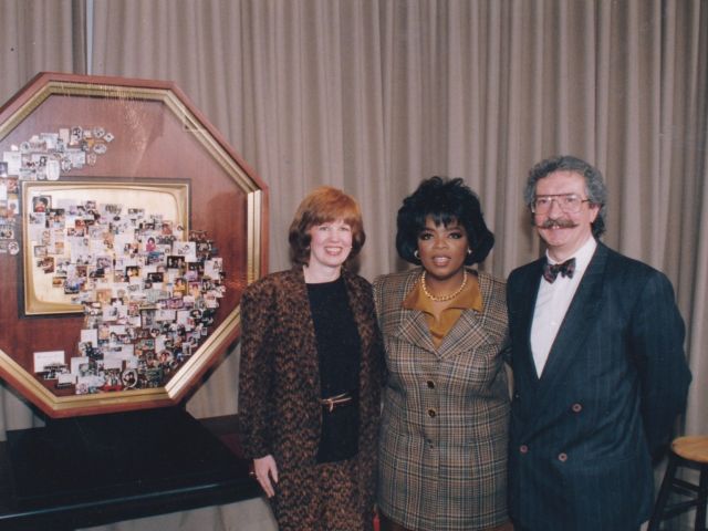 Oprah Winfrey standing next to Artist Lawrence Romorini and Studio Director Donna Rome in front of a large shadow box collage honoring her career