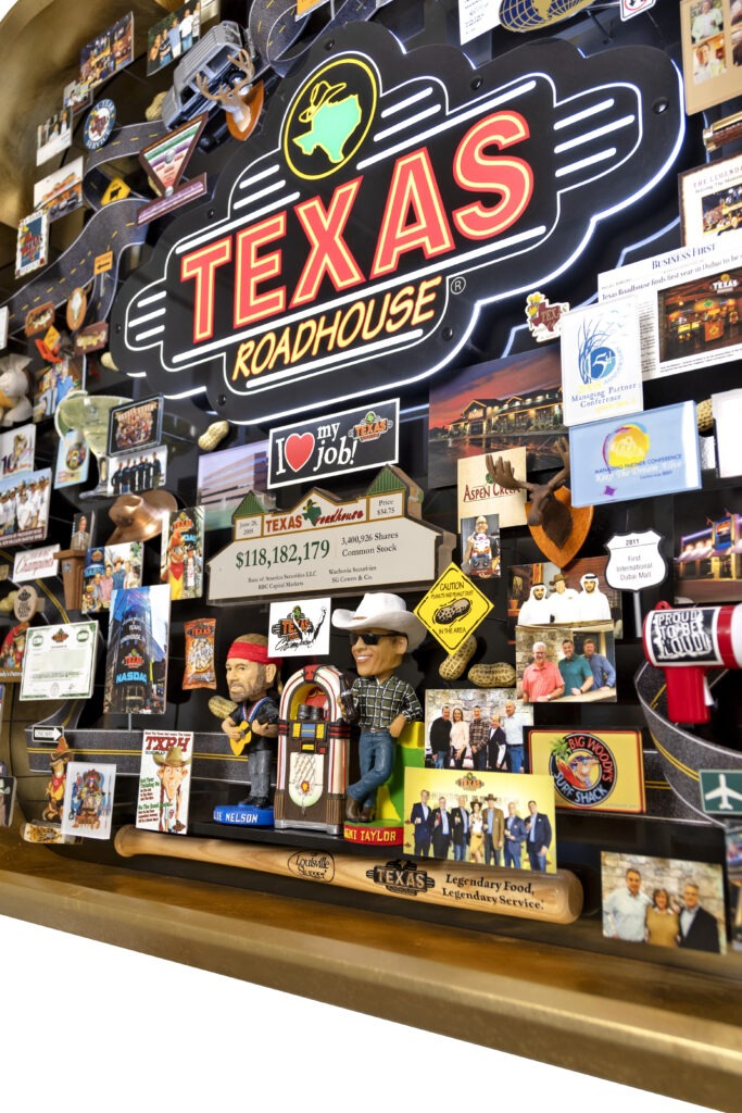 Large collage for Texas Roadhouse featuring bobble head of Willie Nelson next to juke box, Louisville Slugger bat, neon sign. 