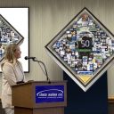 Speaker at podium looking at Data Sales 50th Anniversary collage on a stand