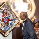 Goode Companies' CEO smiling while looking at a shadow box collage that commemorates their 25th anniversary