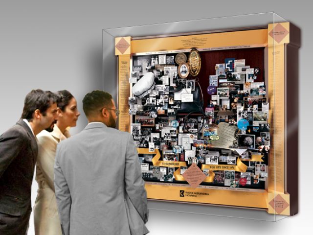 People looking at large shadow box collage commemorating Inova Alexandria Hospital's 125-year retrospective