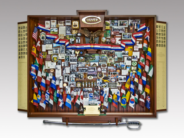 Shadow box collage commemorating Culver Academies Chairman with over 50 miniature flags and sword