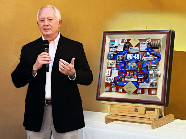 WD-40 Retiring Board Chairman standing next to artwork