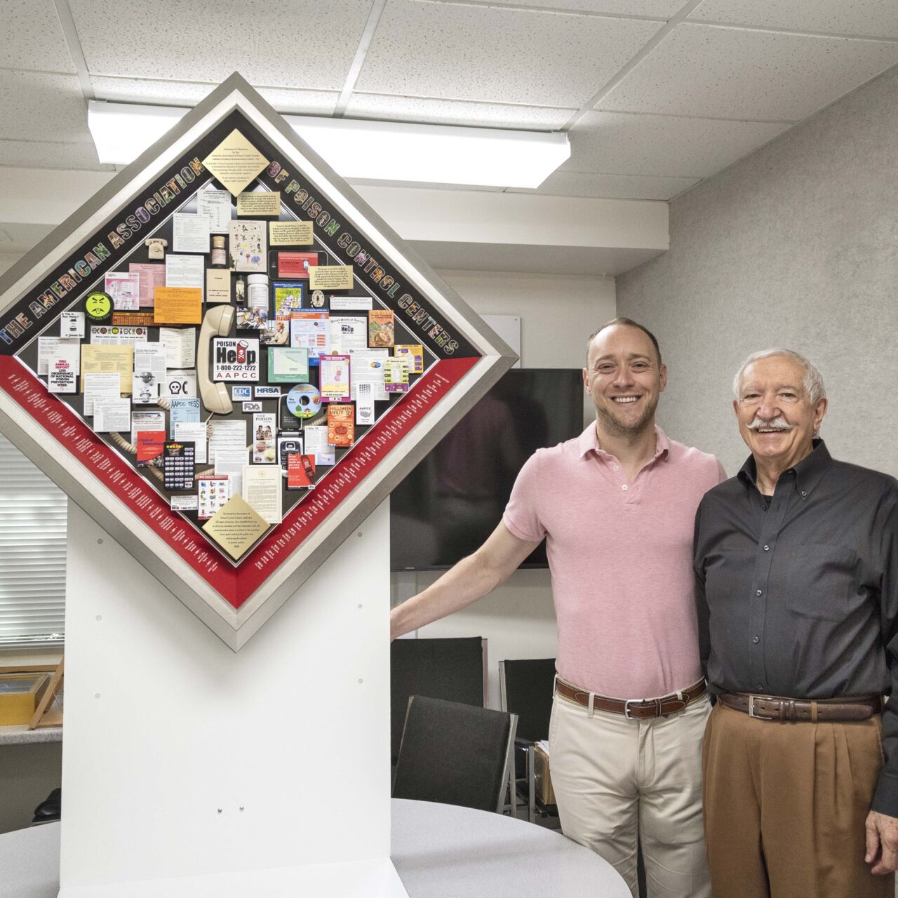Artist and client standing next to educational collage for the American Association of Poison Control Centers 